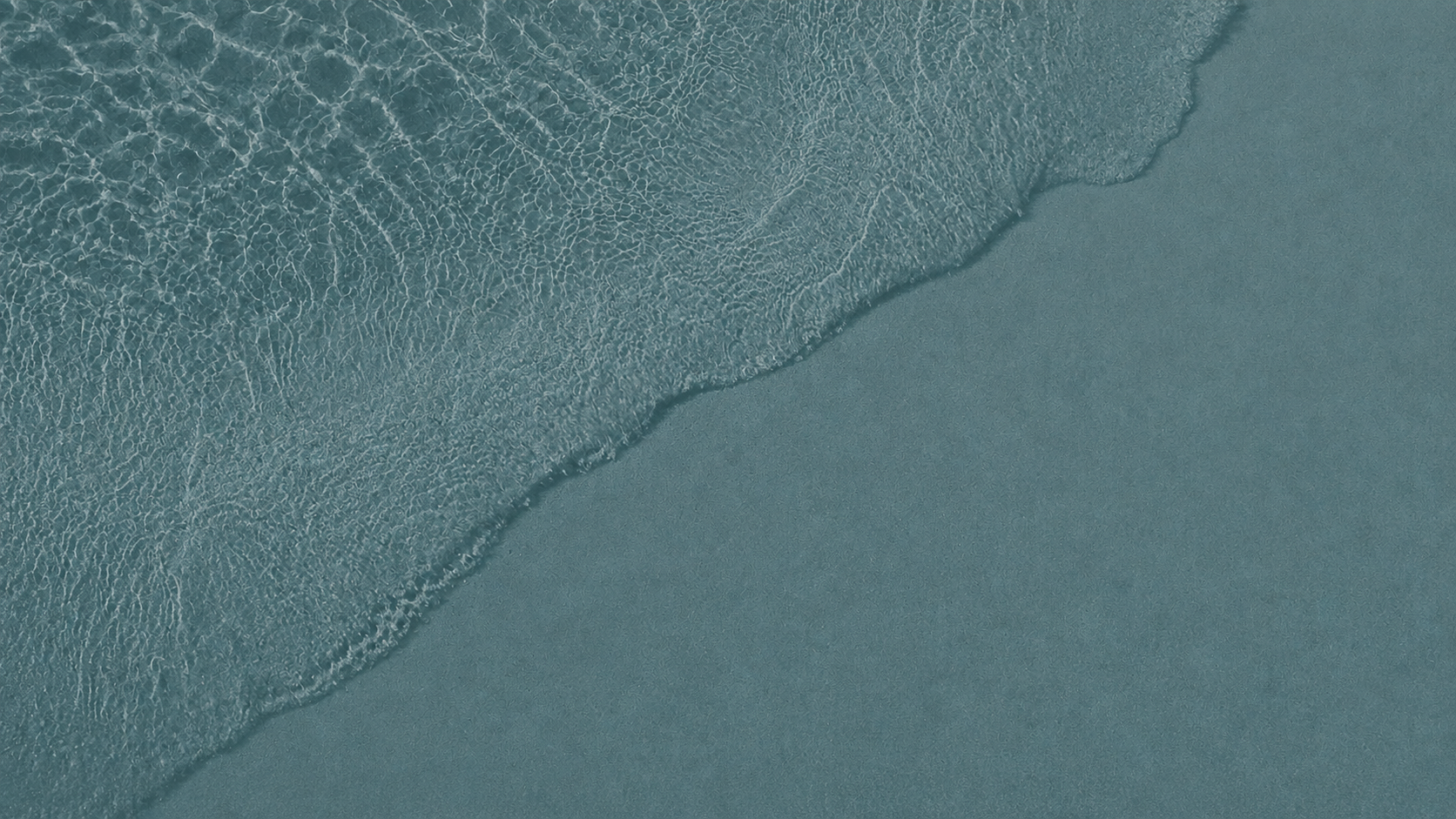 Sea foam dissolving over pale sand